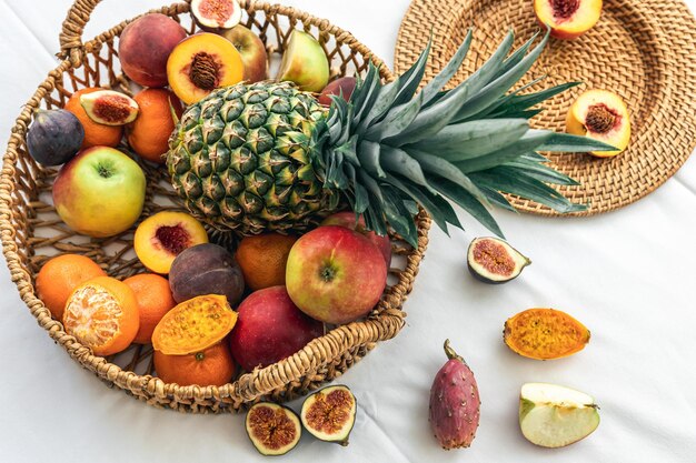 Ananas et autres fruits exotiques dans un panier en osier sur fond blanc