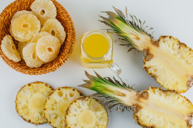 Ananas avec du jus et des anneaux confits sur une surface blanche