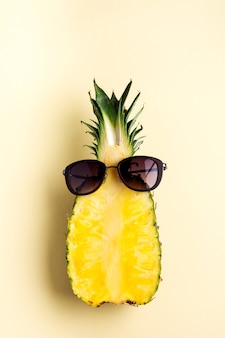 Ananas frais coupé en deux parties, cahier ou carnet de croquis et lunettes de soleil sur fond jaune. notion d'été. mise à plat créative avec espace de copie. vue de dessus