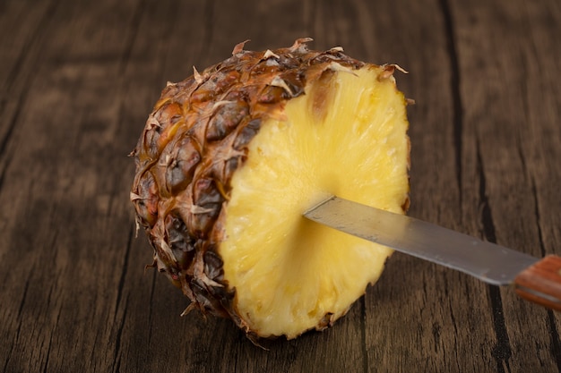 Ananas Frais Tropical Avec Un Couteau Sur Une Surface En Bois. Photo Premium
