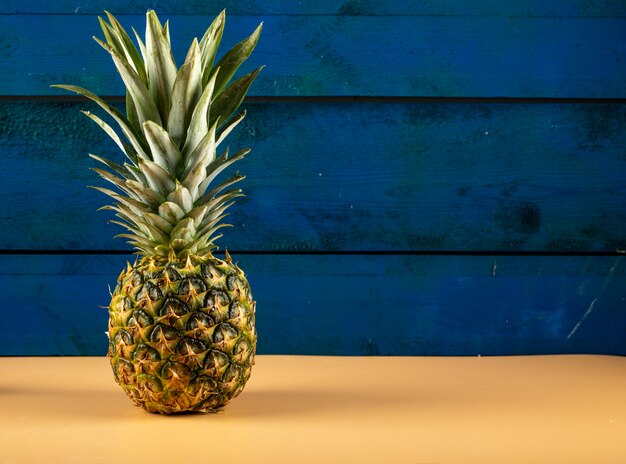 Ananas isolé sur un mur bleu sur la table de couleur orange