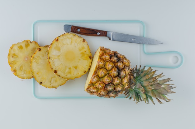 Ananas en tranches avec un couteau sur une planche à découper