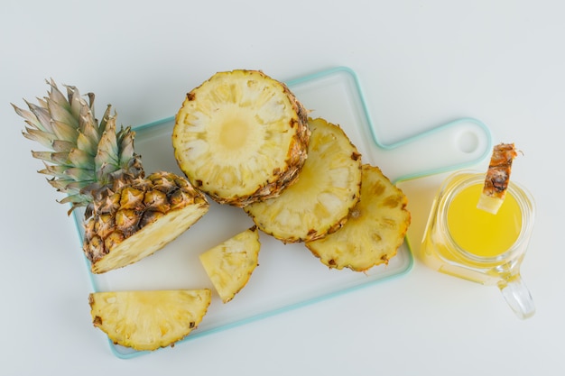 Ananas en tranches avec du jus sur blanc et planche à découper