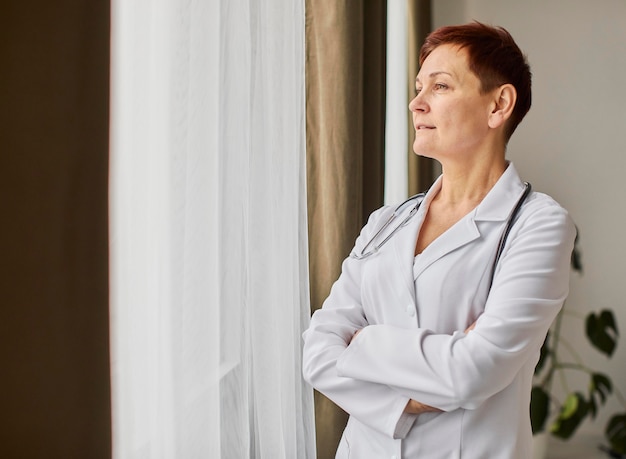 Ancien centre de récupération de Covid femme médecin regardant par la fenêtre avec copie espace