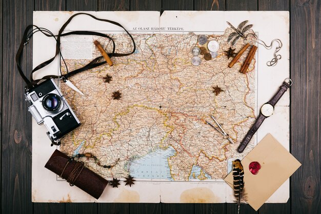 Ancienne carte jaune, lunettes, pièces de monnaie, étui en cuir, appareil photo, montre, boussoles, grains de café, d&#39;autres épices et biscuits se trouvent sur le plancher en bois