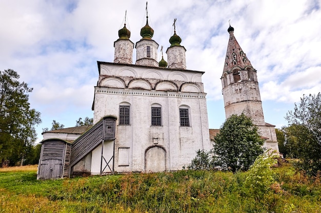 Ancienne église orthodoxe au village. Vue d'été avec prairie fleurie. Journée ensoleillée, ciel bleu avec des nuages.