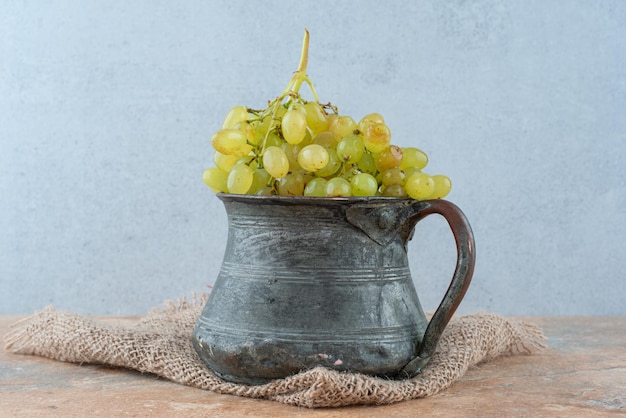 Une ancienne tasse pleine de raisins sucrés sur marbre