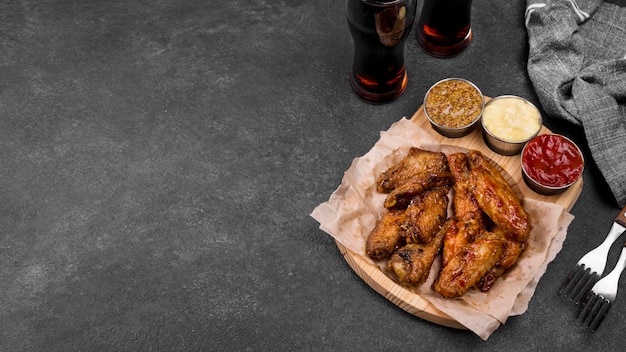 Photo gratuite angle élevé d'ailes de poulet frit avec une variété de sauces et de boissons gazeuses