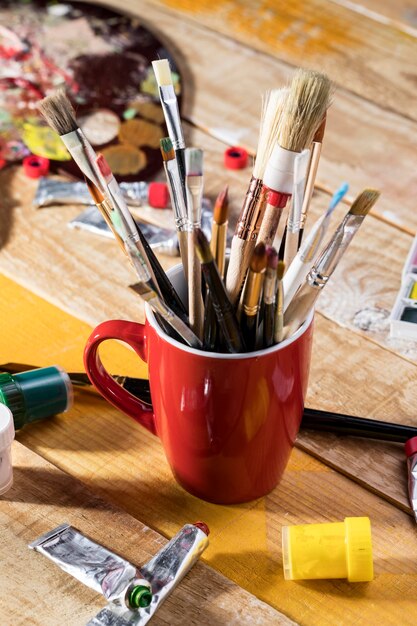 Angle élevé d'assortiment de pinceaux dans une tasse avec palette