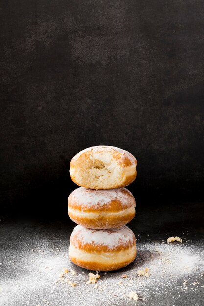 Angle élevé de beignets empilés avec du sucre en poudre