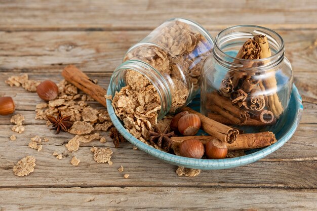 Angle élevé de bocaux avec céréales pour petit déjeuner et bâtons de cannelle