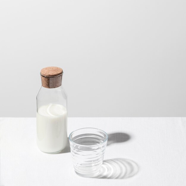 Angle élevé de bouteille de lait avec verre vide