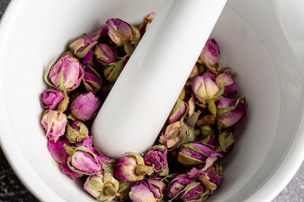 Angle élevé de boutons de rose dans un mortier avec un pilon