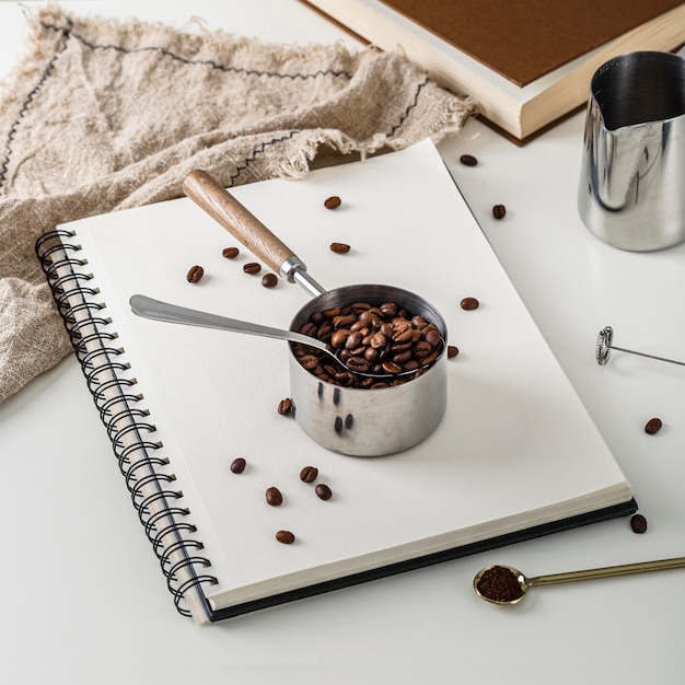 Angle élevé de cahier avec tasse de grains de café torréfiés