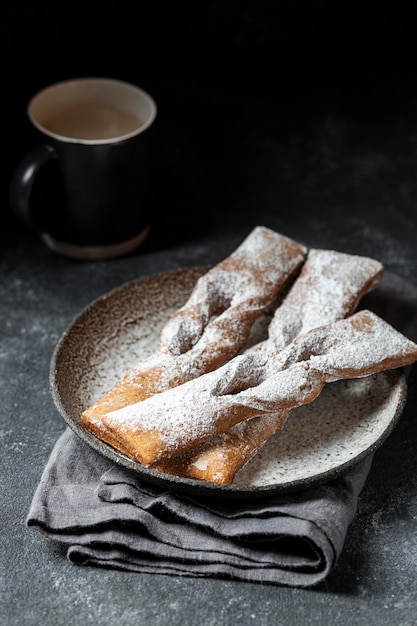 Angle élevé de desserts recouverts de sucre en poudre avec café