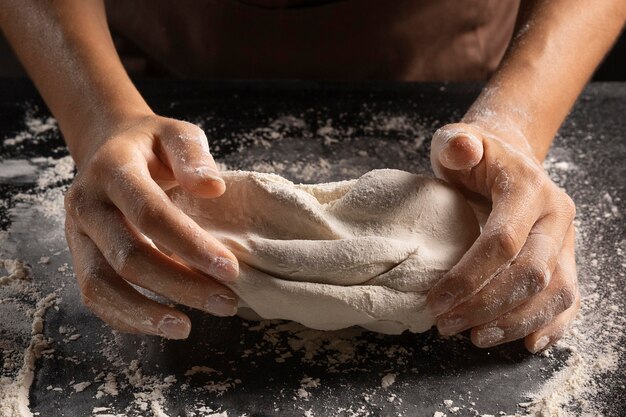 Angle élevé du chef pétrir la pâte avec les mains