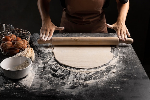 Photo gratuite angle élevé du chef à rouler la pâte avec de la farine