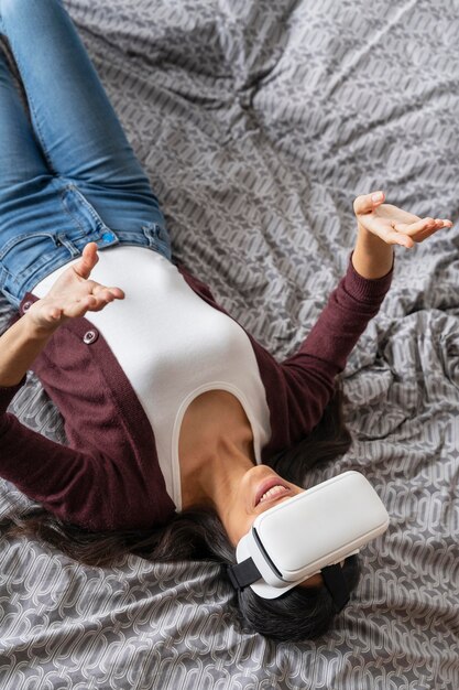 Angle élevé de femme à l'aide d'un casque de réalité virtuelle au lit
