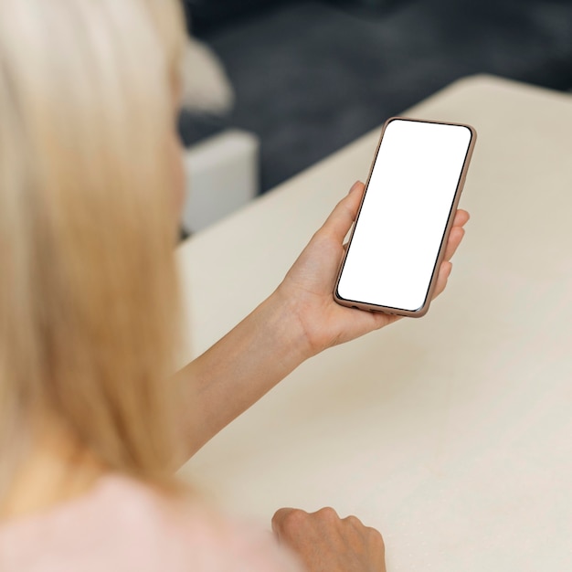 Angle élevé de femme à l'aide de smartphone à la maison pendant la pandémie