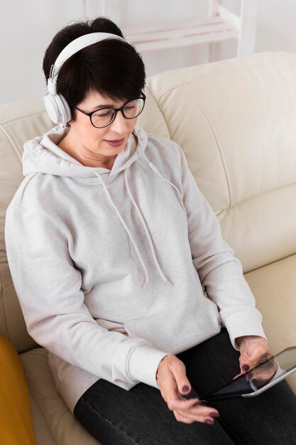 Angle élevé de femme sur le canapé avec un casque et une tablette