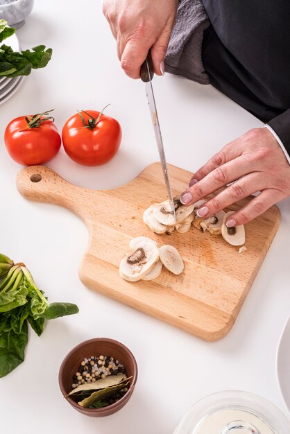 Angle élevé de femme chef coupant les champignons