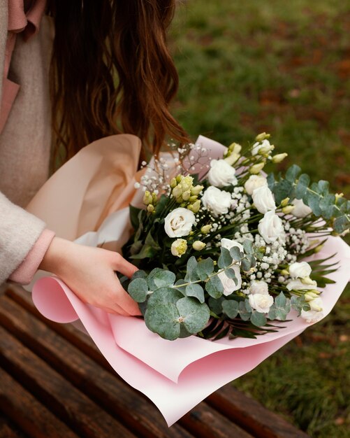 Angle élevé de femme élégante avec bouquet de fleurs à l'extérieur
