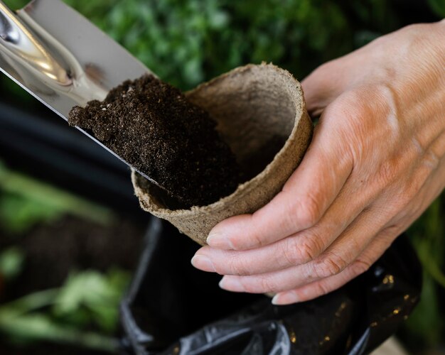 Angle élevé de femme mettant le sol en pot pour la plantation