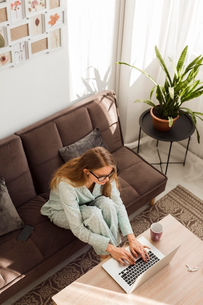 Angle élevé de la femme en pyjama travaillant à la maison