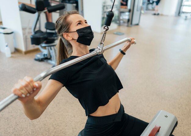 Angle élevé de femme travaillant à la salle de sport pendant la pandémie