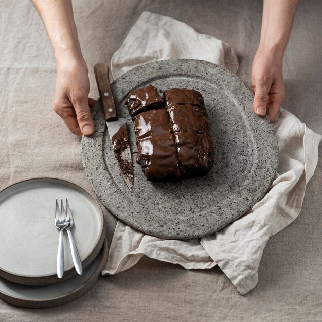 Angle élevé de gâteau au chocolat sur la plaque tenue par le chef pâtissier