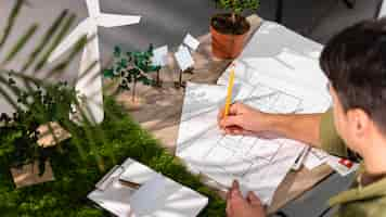 Photo gratuite angle élevé de l'homme travaillant sur un projet d'énergie éolienne écologique avec des plans papier