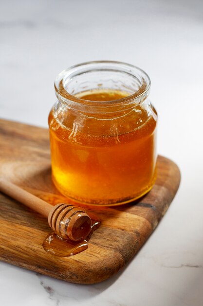 Angle élevé de louche à miel en bois à côté d'un pot de miel