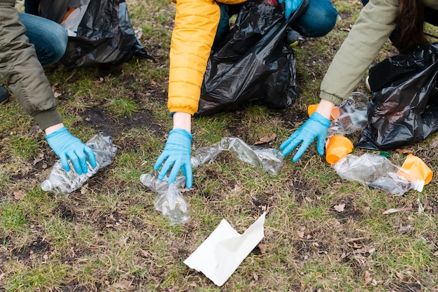 Angle élevé des mains saisissant les bouteilles en plastique