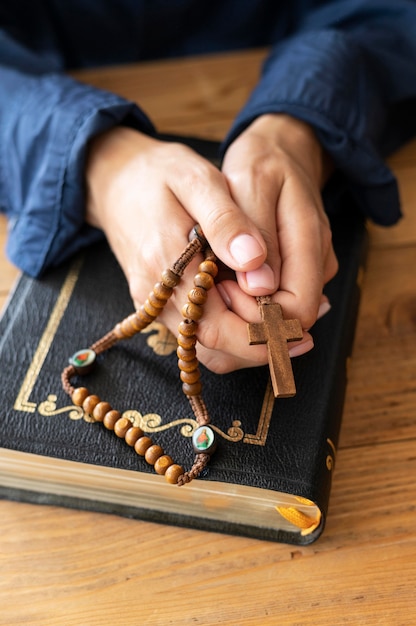 Angle élevé de personne priant avec chapelet et croix