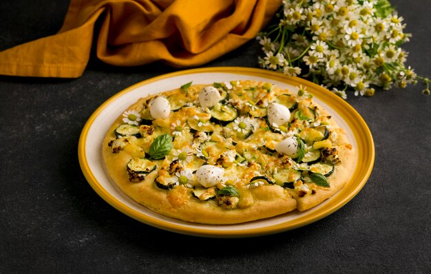 Angle élevé de pizza sur plaque avec fleurs de camomille