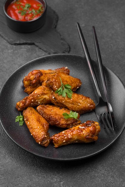 Angle élevé de poulet frit sur assiette avec couverts et sauce