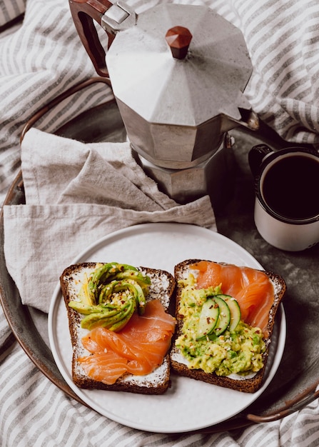 Angle élevé de sandwiches au petit-déjeuner au saumon et à l'avocat au lit