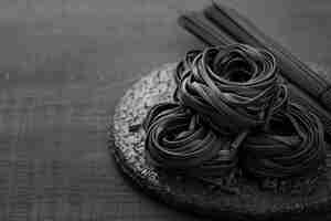 Photo gratuite angle élevé de tagliatelles noires sur une plaque avec des spaghettis