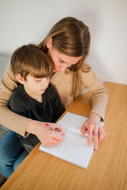 Photo gratuite angle élevé de tutrice enseignant à l'enfant à la maison