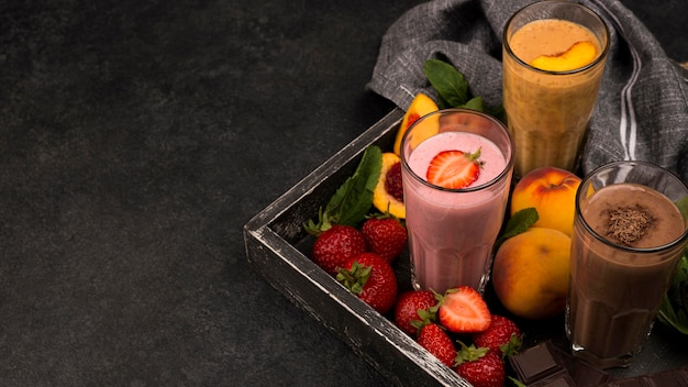 Angle élevé de verres de milkshake sur plateau avec chocolat et fruits