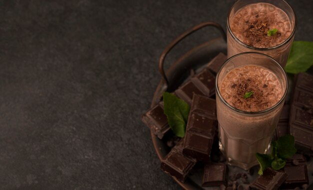 Angle élevé de verres de milkshake sur le plateau avec du chocolat et de l'espace de copie