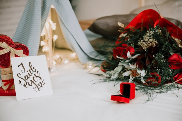 Anneau et fleurs près de la pile de cadeaux