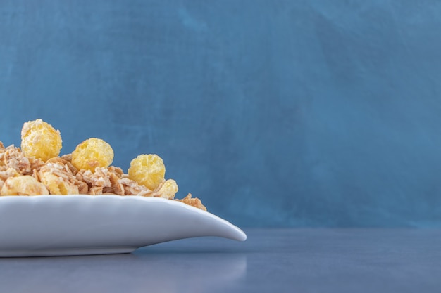 Anneau de maïs au miel avec muesli dans une assiette, sur la table en marbre.