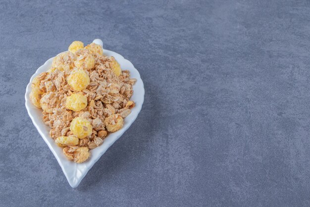 Anneau de maïs au miel avec muesli dans une assiette, sur la table en marbre.