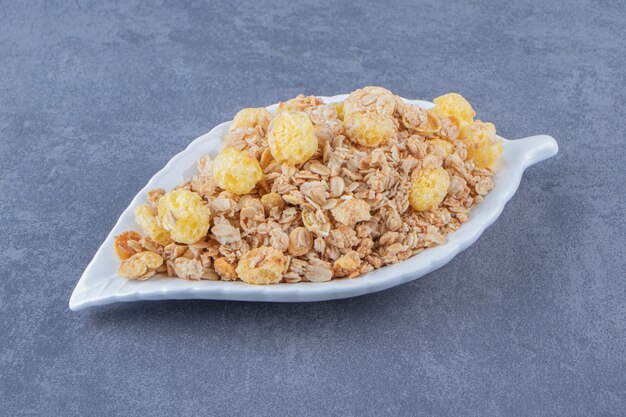 Anneau de maïs au miel avec muesli dans une assiette, sur la table en marbre.