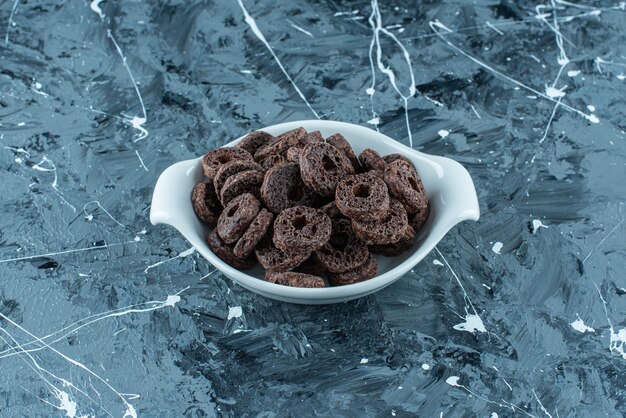 Anneau de maïs enrobé de chocolat dans un bol, sur le fond de marbre.