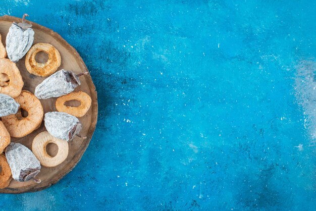 Anneaux de pomme séchée et kaki sur une planche , sur la table bleue.