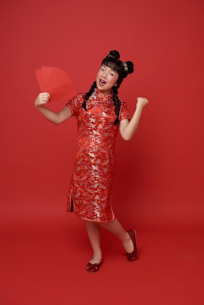 Photo gratuite année chinoise nouvelle enfant asiatique portant une robe traditionnelle cheongsam qipao tenant une enveloppe rouge