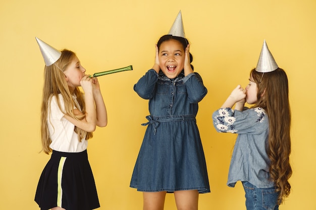 Anniversaire de petits enfants isolé sur mur jaune. enfants tenant un gâteau.