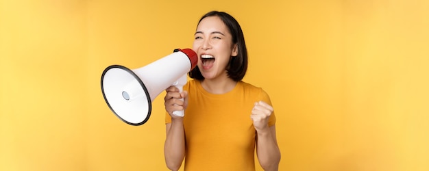 Annonce heureuse femme asiatique criant fort au mégaphone recrutant protestant avec le haut-parleur à la main